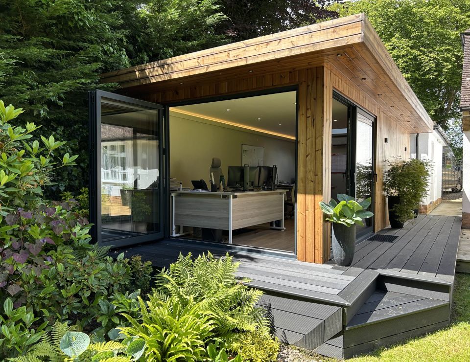 Contemporary garden office pod with large glass doors, wooden cladding, and lush green surroundings, providing a serene and stylish workspace.